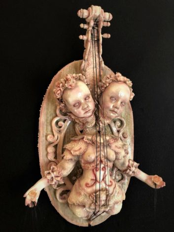mixed media assemblage of two headed painted goth doll with violin handle and strings