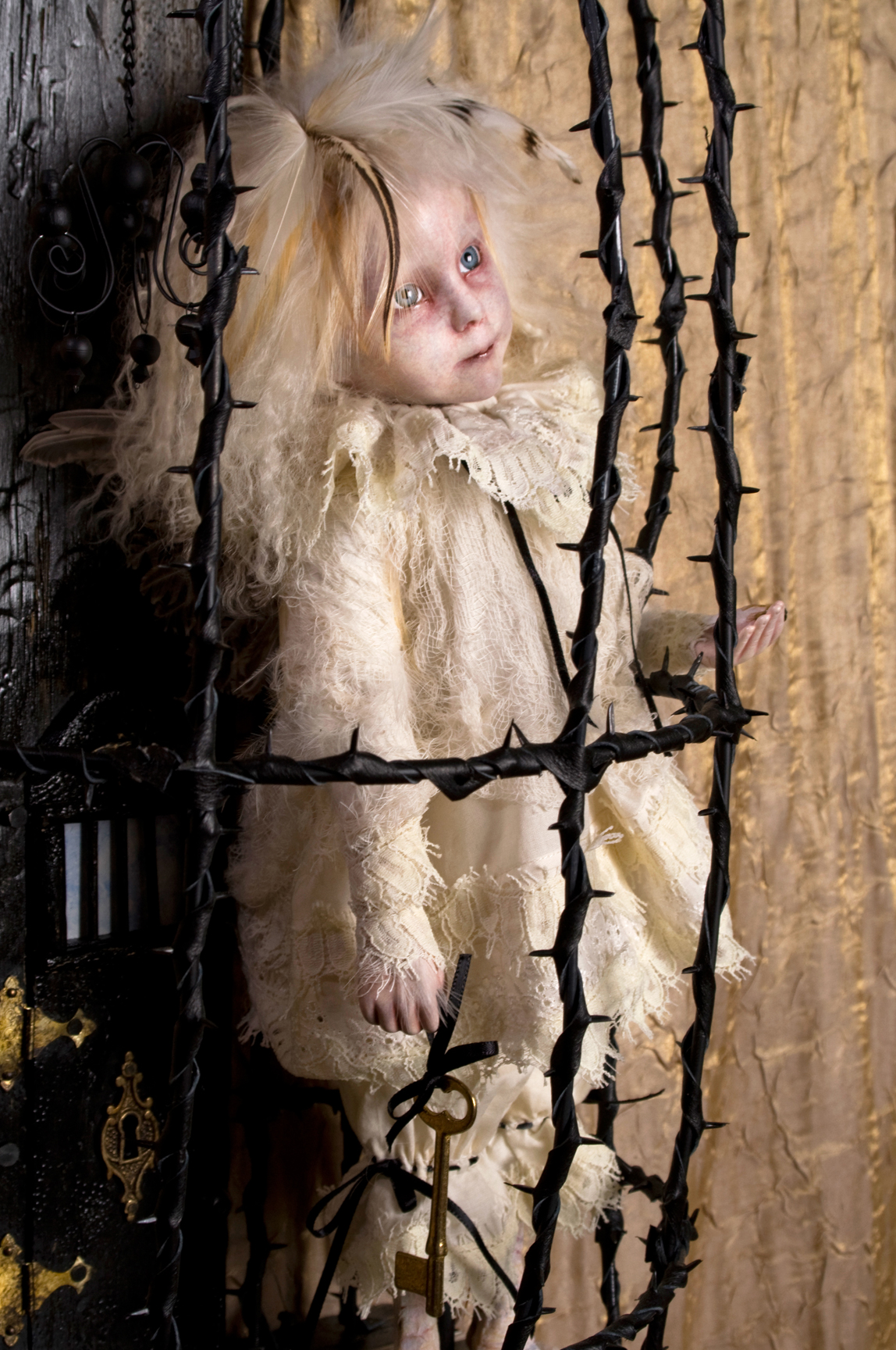 blond feathered pale gothic artdoll wearing white lace in a black thorn cage