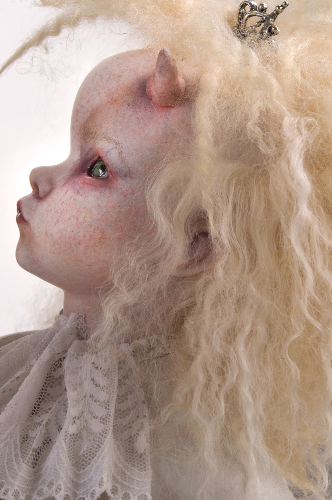 close-up of gothic angel messenger doll white fur mohair wig, horned, pale with white lace collar
