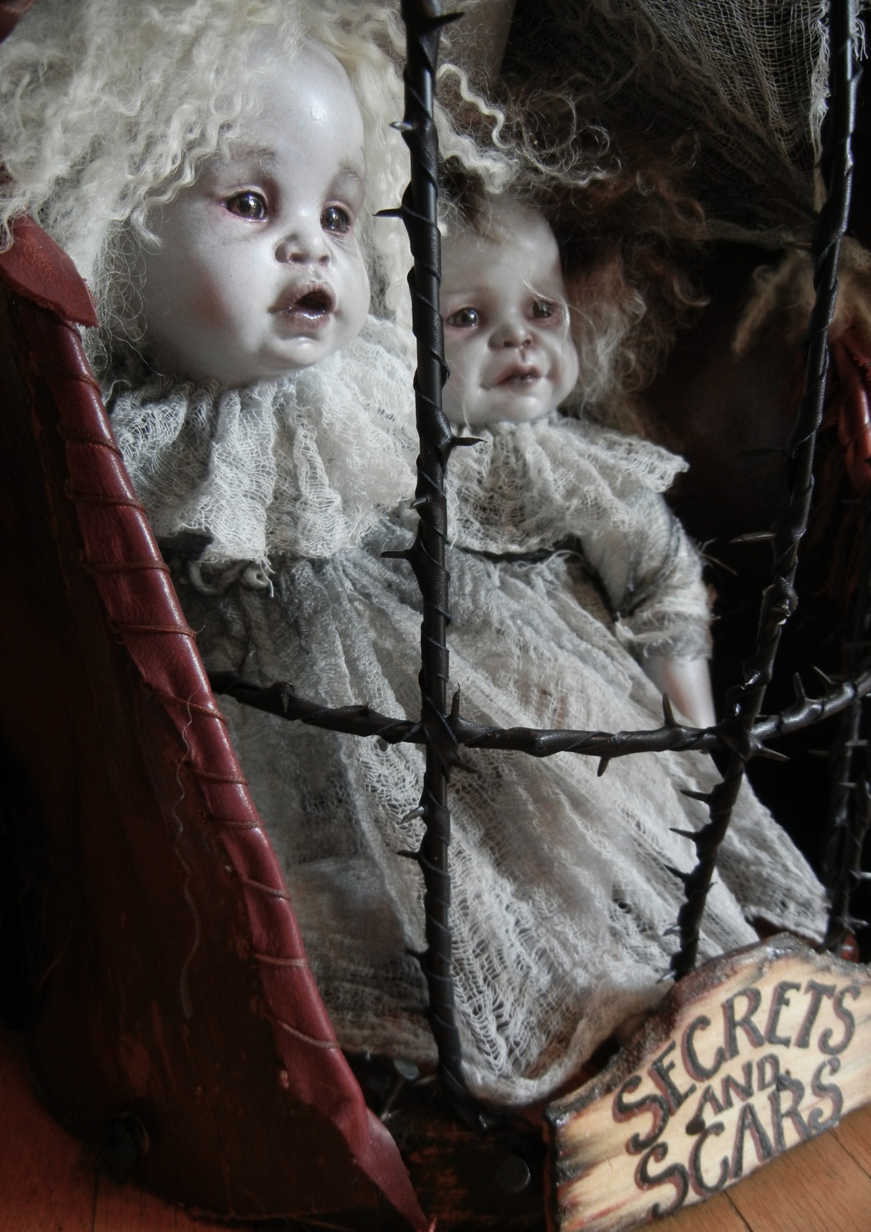 two pale ghostly gothic artdolls dressed in white in a black thorn cage