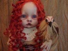 close-up of gothic artdoll with red ringlet hair holding a sculpted bird companion
