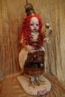 gothic artdoll with red ringlets has sculpted bird companions, a brass cage skirt and hat and taxidermied bird feet stands on wooden platform