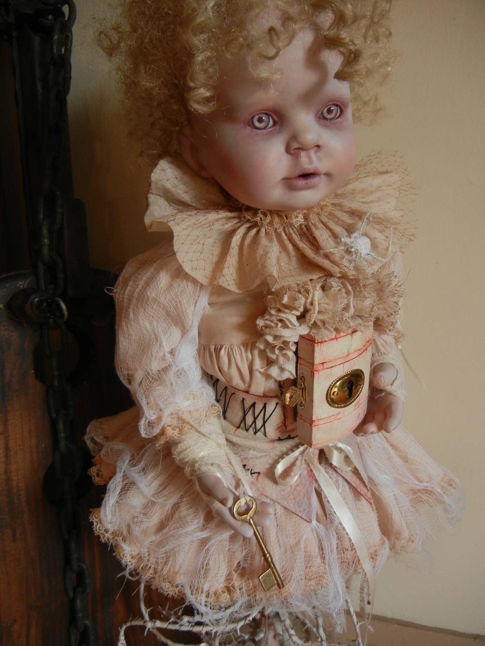 gothic fantasy artdoll mixed media porcelain doll body growing out of white thorny vine she has blond ringlets and pink eyes with a little locked cabinet in her torso