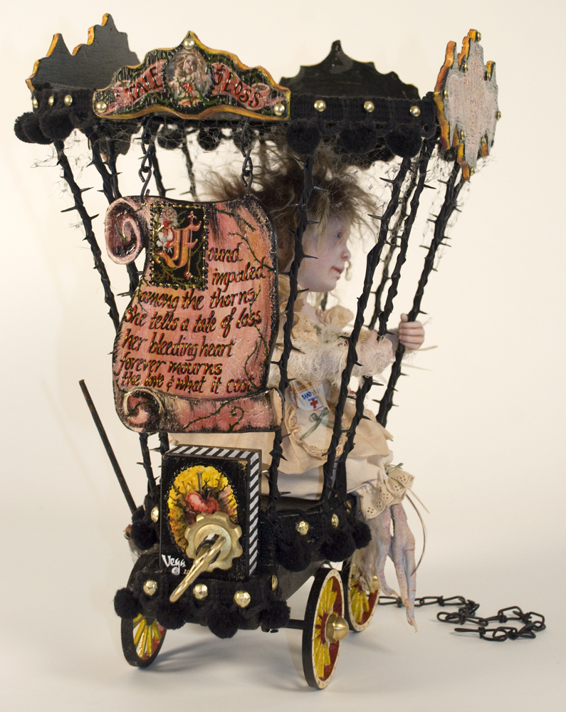 Side view of taxidermy artdoll with bird feet sitting in a caged circus cart sideshow hand-painted freakshow signs