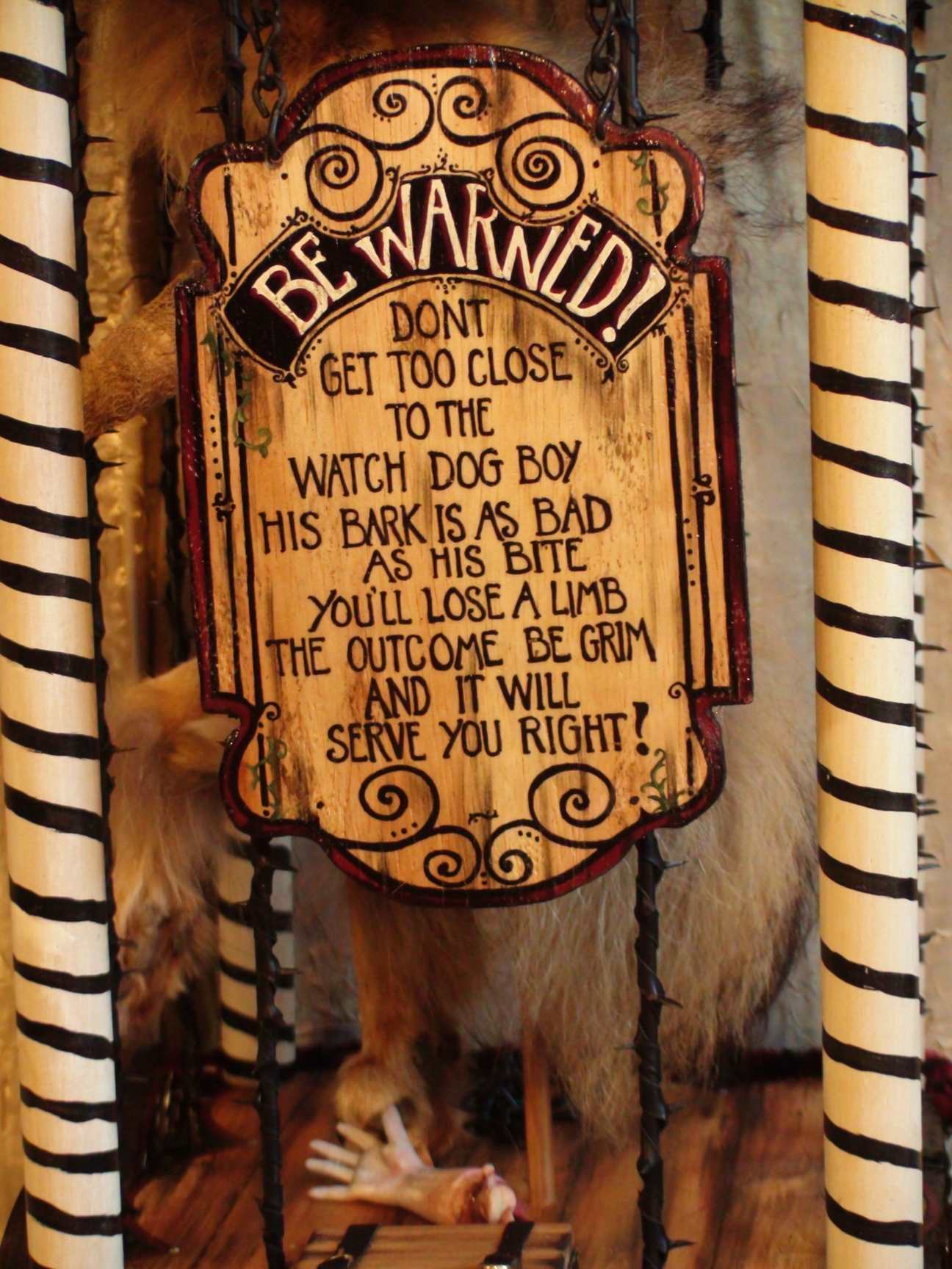 close-up hand painted lettered sign warning about watch dog boy hanging on cage cart circus