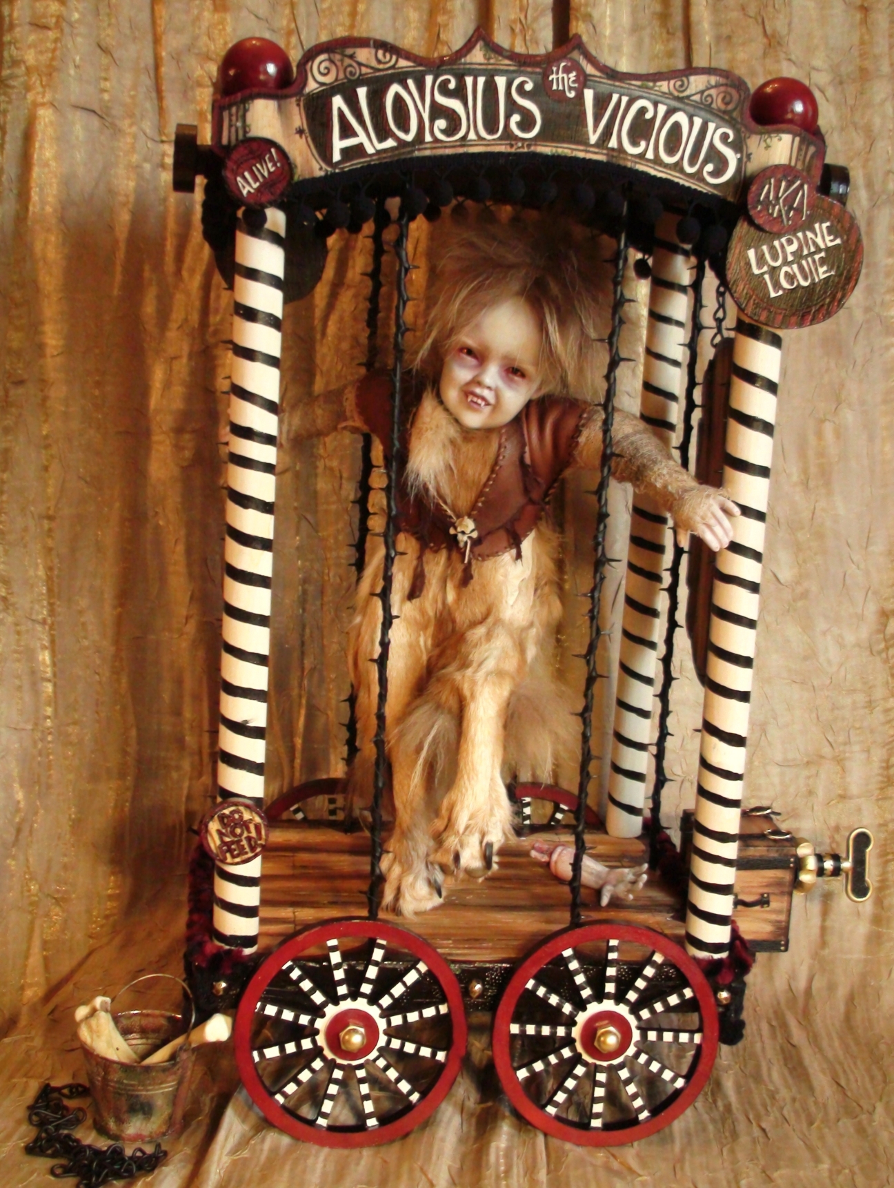 artdoll of a watchdog boy wolf boy sideshow attraction taxidermy assemblage in a cage carnival cart pull toy with hand painted signs and wheels