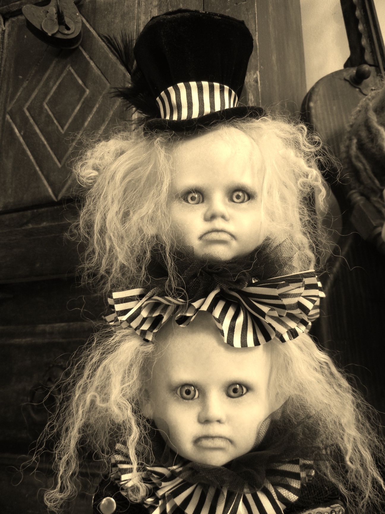 close-up of two goth doll repaints wearing black and white striped collars and a black tophat wild blond hair