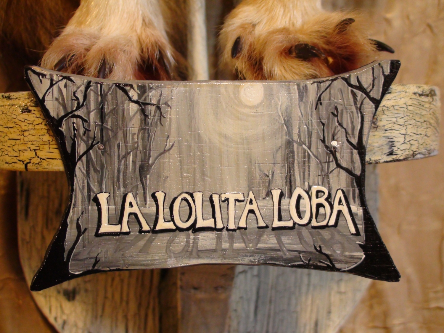 close-up hand painted lettered wooden sign with trees and moon reads La Lolita Loba