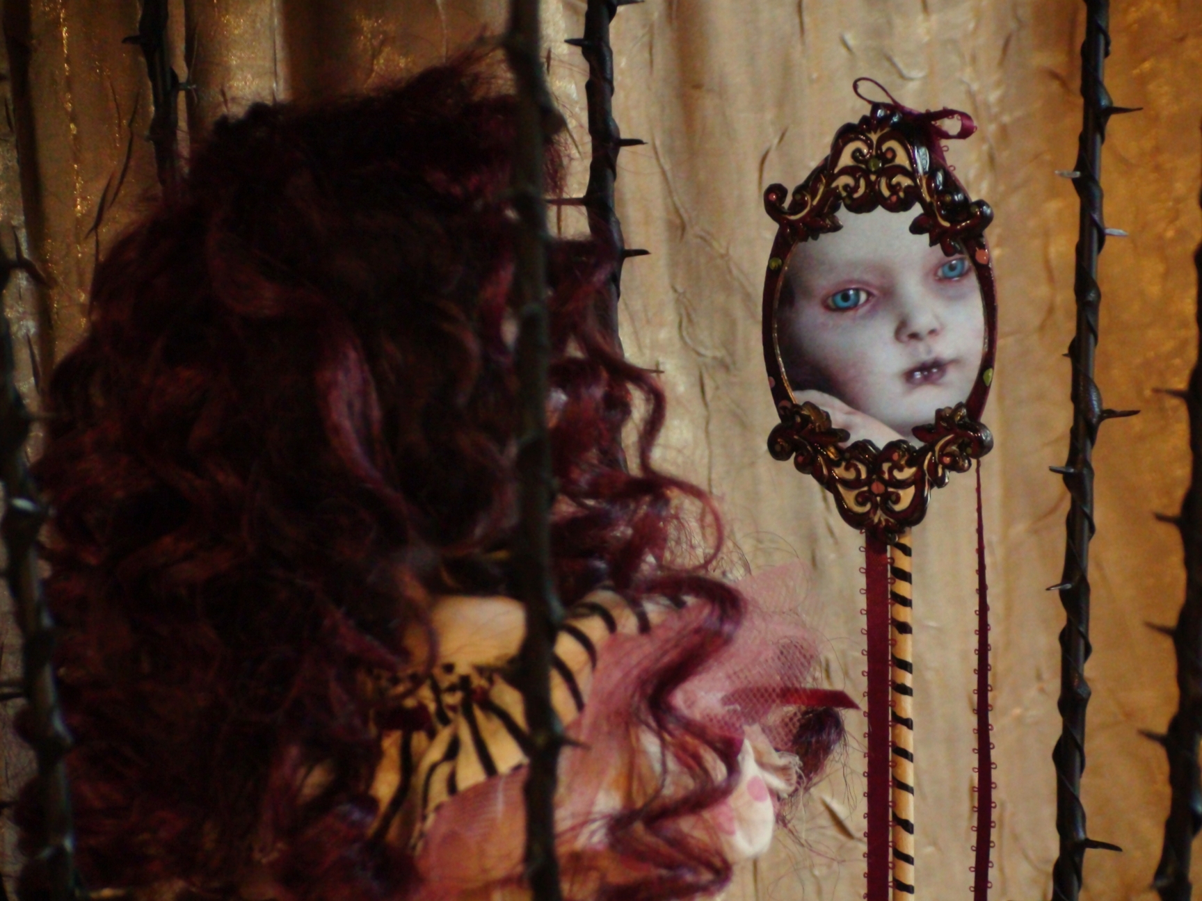close-up of a pale red curly haired circus doll looking into an ornate mirror