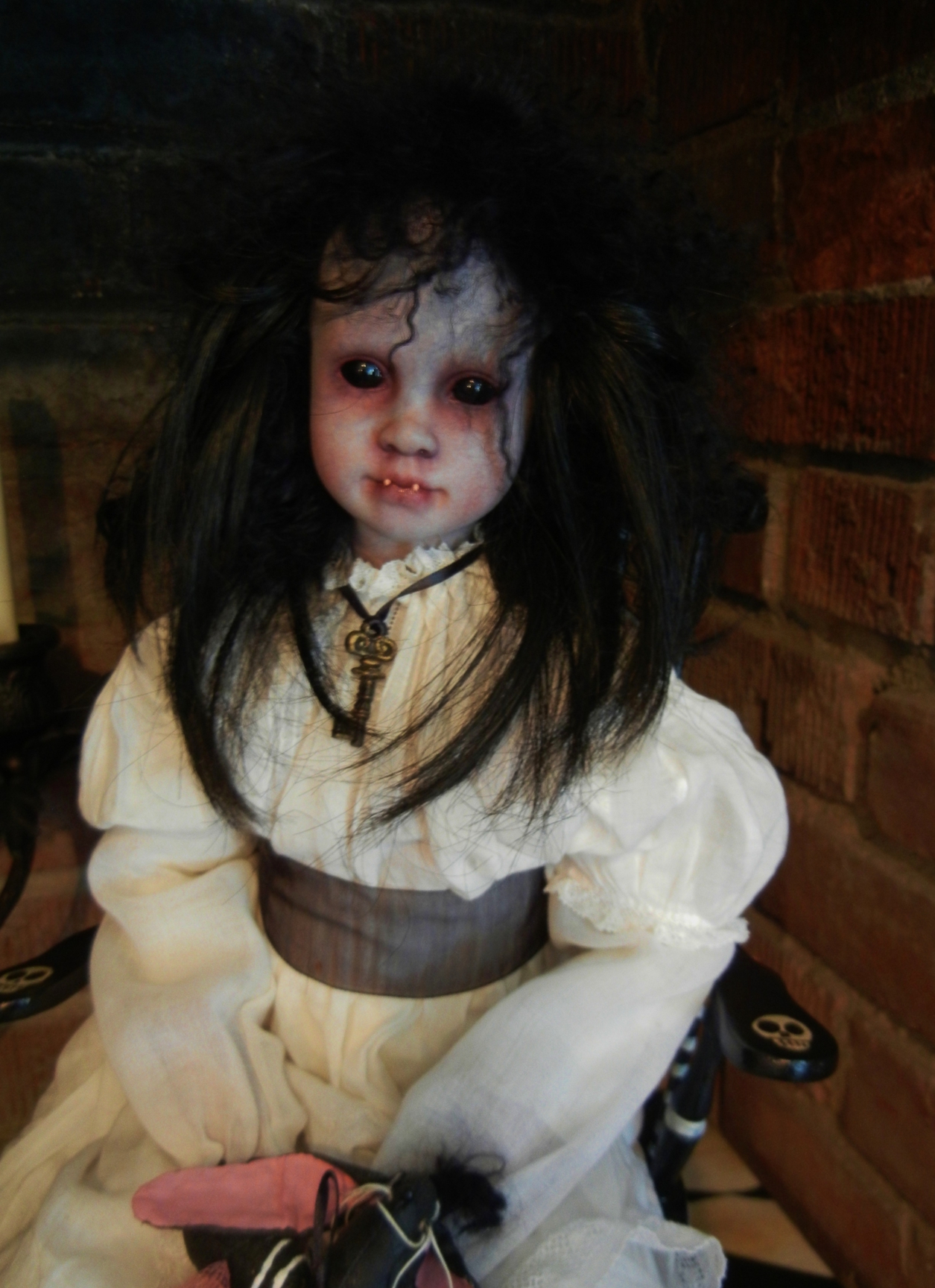 seated gothic artdoll pale porcelain repaint with black hair wearing white victorian blouse and bloomers, key necklace
