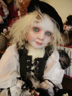 gothic artdoll pale with light eyes and blond hair wearing black beret, white shirt with lace cuffs, leather vest, taxidermy chicken feet holds a feathered pet creature in his lap