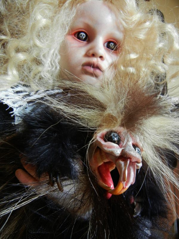 pale gothic artdoll with blond ringlets, skulls in her black eyes, wearing a white dress, carrying black feathered creature sculpture