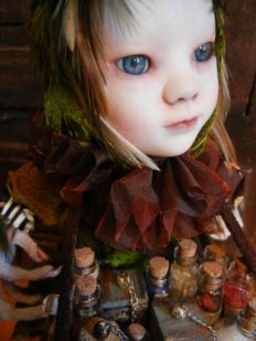 close-up porcelain doll repaint gothic face, blue eyes wearing ruffled collar with bird feathers for hair holding assorted glass bottles