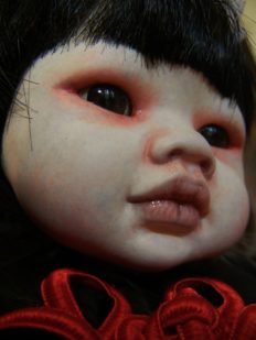 close-up gothic Asian Chinese porcelain doll repaint with red rimmed eyes pale skin black bangs