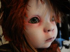 close-up gothic repaint porcelain doll head with blue eyes, feather hair