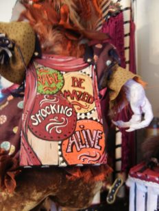 close-up circus-themed sideshow hand painted sign board doll with taxidermy birdfeet
