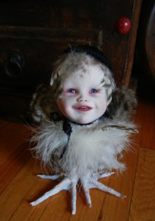 mixed media gothic victorian artdoll porcelain babydoll head wearing black cap and ribbon on light feathered bird body with taxidermy bird feet