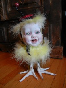 mixed media gothic victorian artdoll porcelain babydoll head wearing black cap and ribbon on yellow feathered bird body with taxidermy bird feet