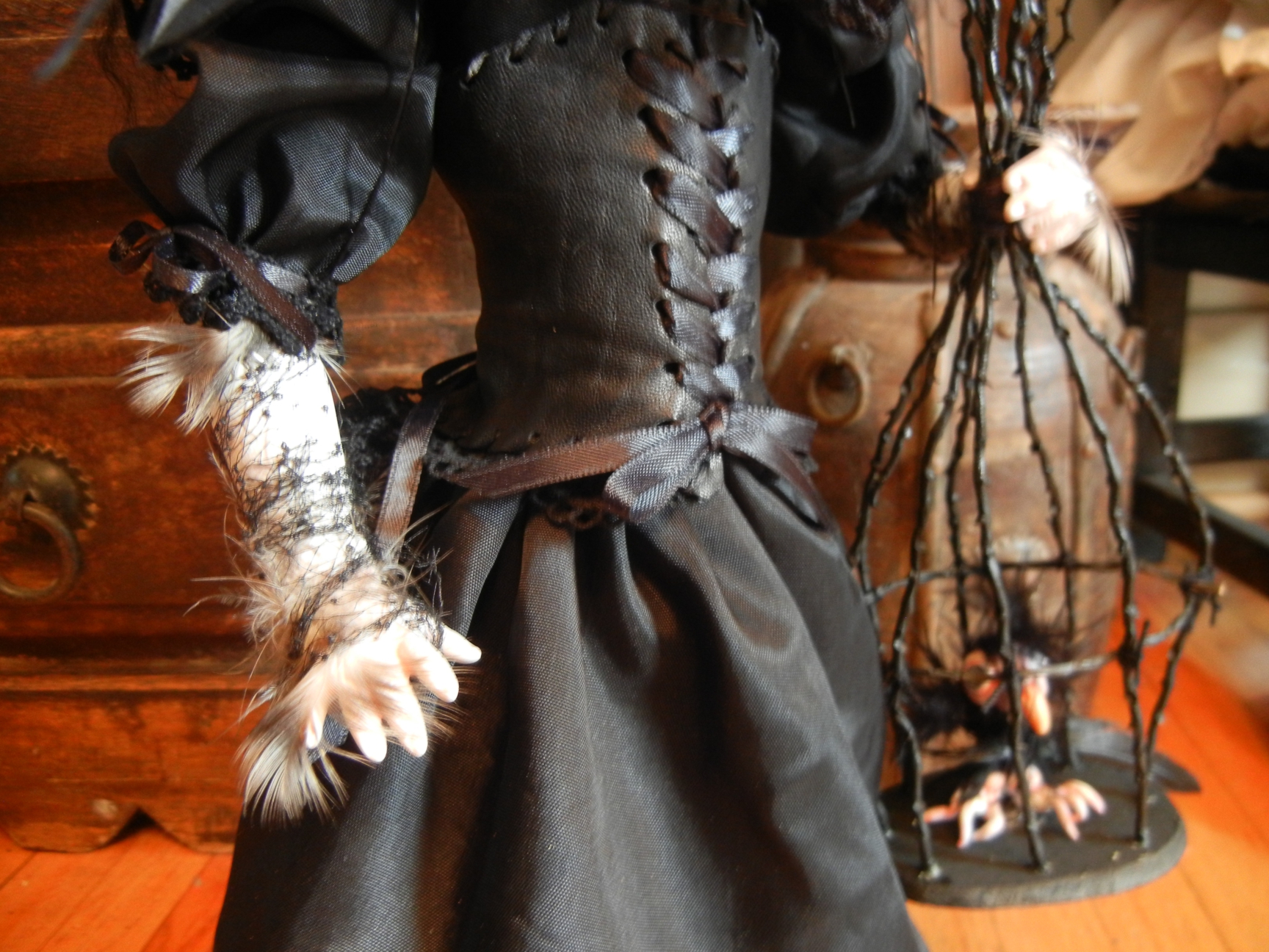 gothic doll torso wearing black corset dress and holding a pet bird in a handmade thorn birdcage