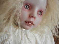 close-up repaint vampire artdoll pale with red rimmed light gray eyes, white blond hair and fangs