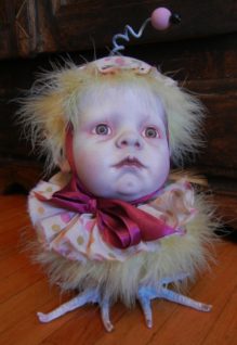 gothic repainted porcelain babydoll head, polka-dot cap and ruff, yellow feathered bird body with taxidermy birdfeet