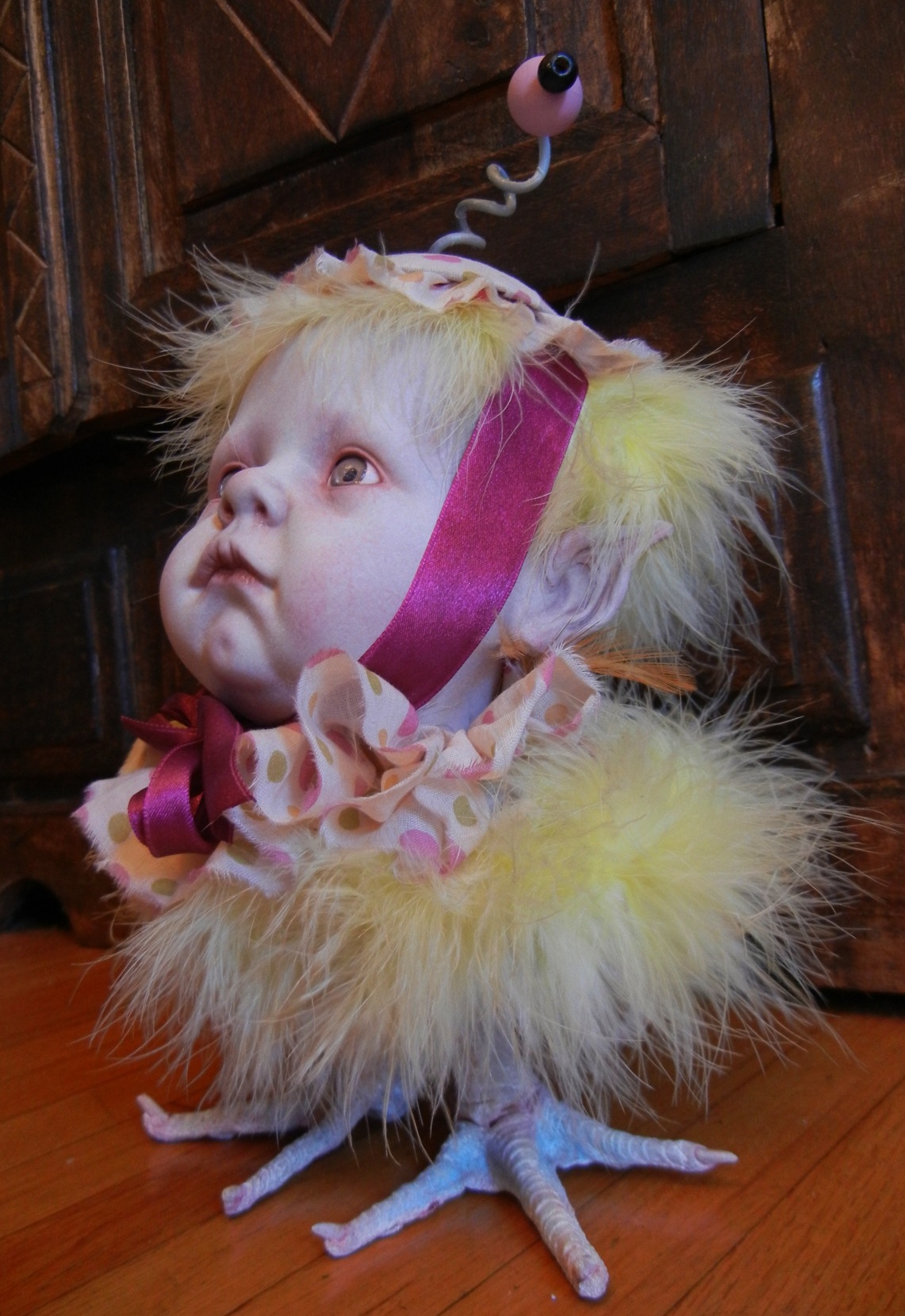gothic repainted porcelain babydoll head, polka-dot cap and ruff, yellow feathered bird body with taxidermy birdfeet