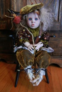 hobo artdoll with taxidermy birdfeet, wearing green brown velvet repainted porcelain doll with curly blond hair carries stick with cloth bundle tied to it