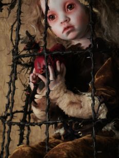 close-up mixed media assemblage art doll sorrowful doll dressed in velvet sits in cage