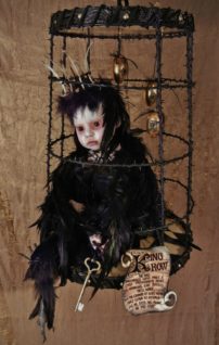 taxidermy artdoll mixed media assemblage of a hapless crowned black-feathered crow doll sitting forlornly in a cage