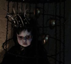 taxidermy artdoll assemblage of a hapless crowned black-feathered crow doll sitting forlornly in a cage bone crown