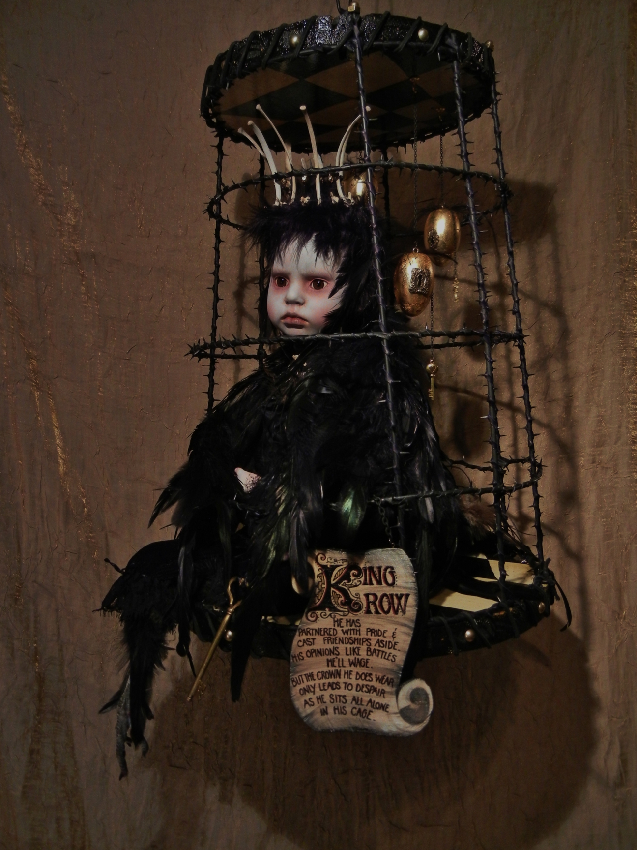 taxidermy artdoll assemblage of a hapless crowned black-feathered crow doll sitting forlornly in a cage