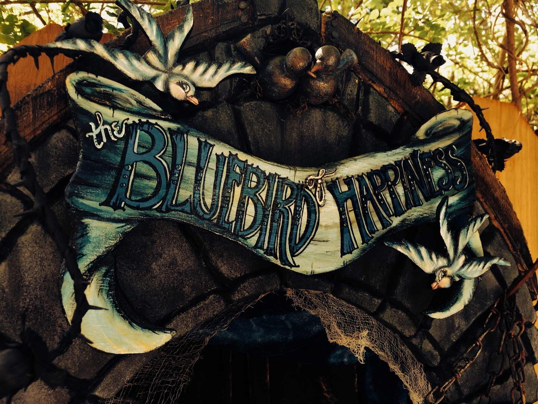 close-up detail hand painted wooden sign reads the Bluebird of Happiness