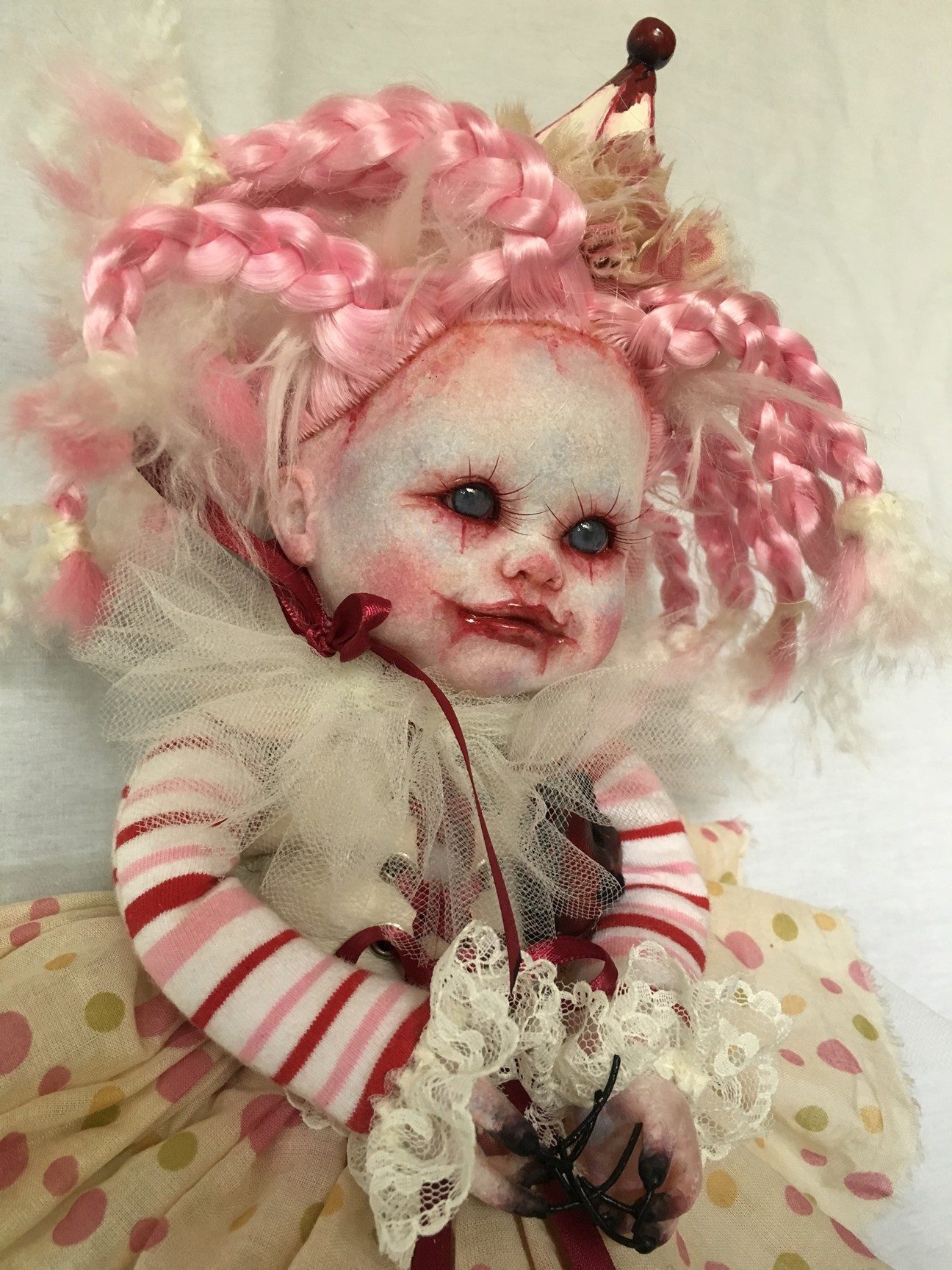 close-up face gothic repaint porcelain doll dark circus clown makeup with pink and white braids, party hat, striped and polka-dot dress