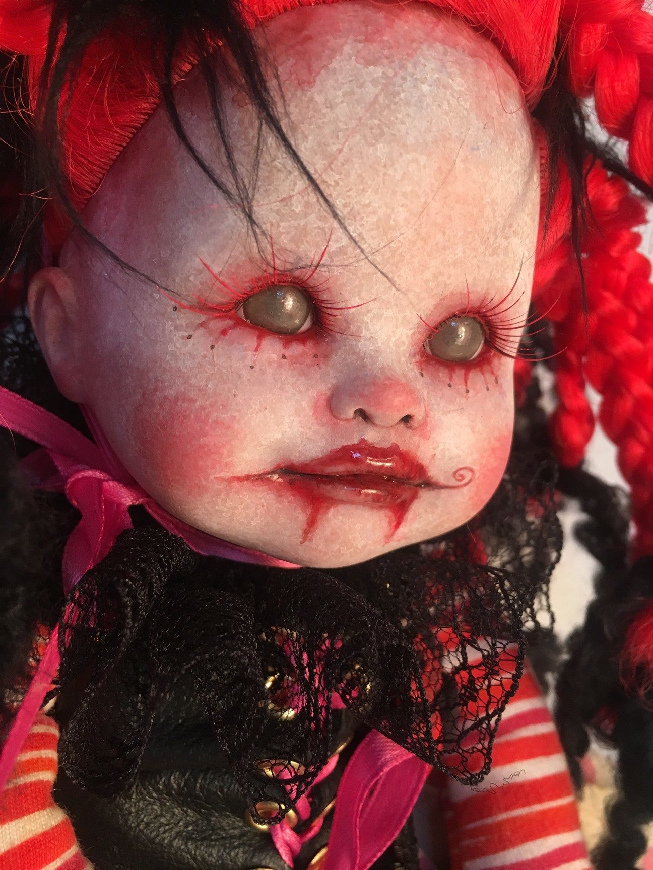 close-up face gothic repaint porcelain doll dark circus clown makeup with bright red and black braids,