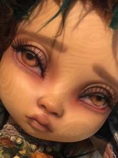 close up of gothic repaint of vinyl doll face big eyes and lashes