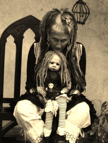 sepia portrait of dark artist Stefanie Vega with a doll in her lap