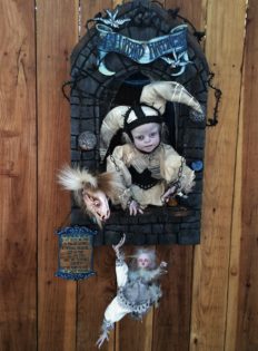 gothic artdoll wearing white jester cap holds chained smaller bird artdoll from inside his carved shadowbox hand-painted letter sign