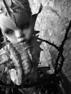 close-up of snake woman hybrid artdoll in a black thorned cage