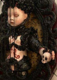 close up mixed media assemblage dark art doll violin holding a skull