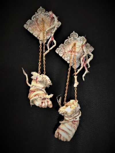 wall hangings of bandaged and bloody severed baby doll feet on chains