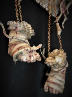 close up of art piece severed baby doll feet bandage wrapped bloody