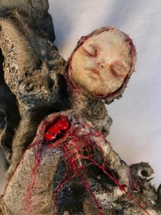 close up of open bleeding heart wounded woman mixed media assemblage sculpture made of porcelain, cloth mache & wood