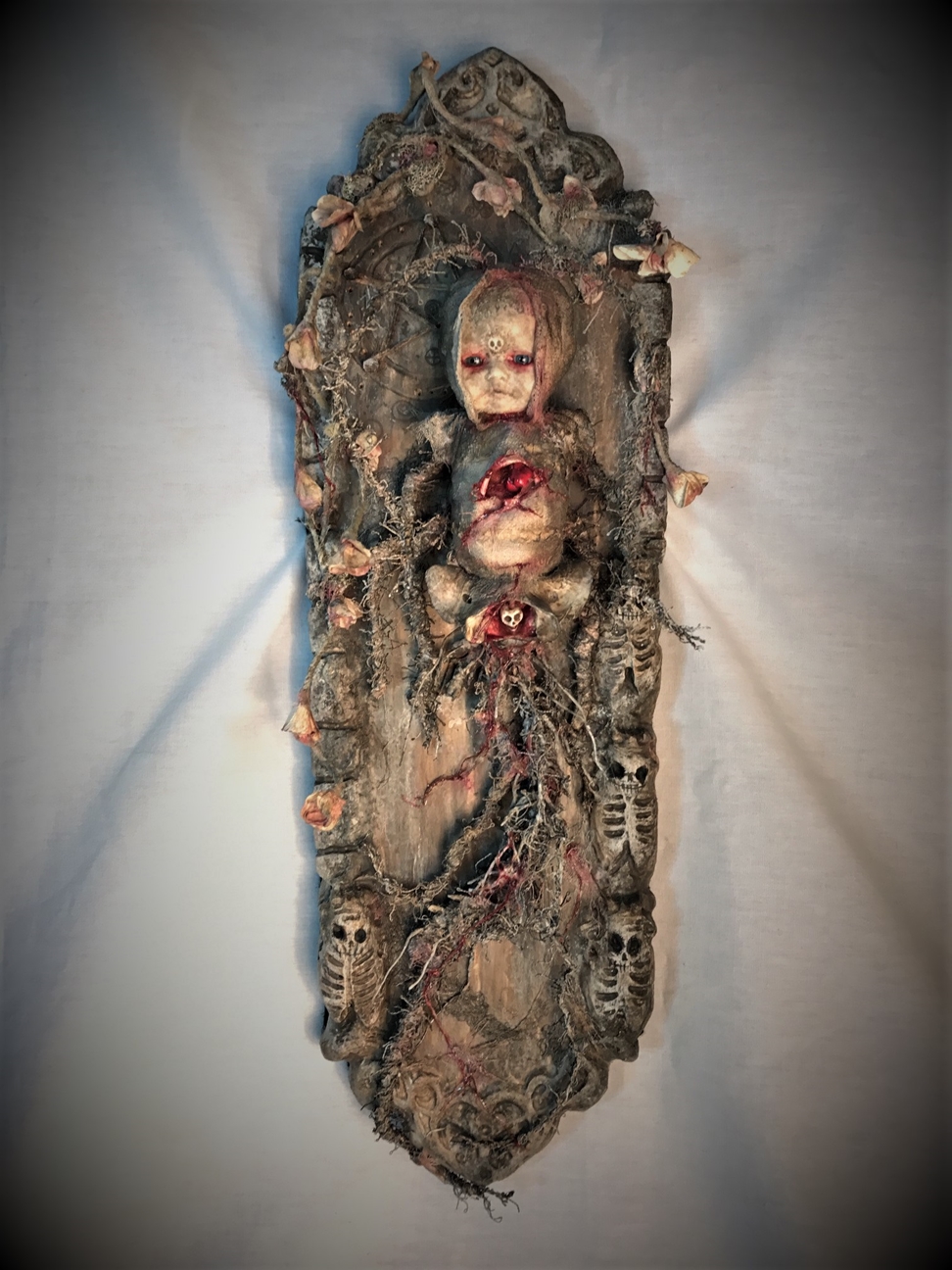 mixed media assemblage ghostly repainted baby doll mounted on wooden board dark art doll split bleeding chest