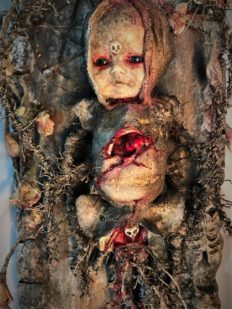 mixed media assemblage ghostly repainted baby doll mounted on board dark art doll split bleeding chest
