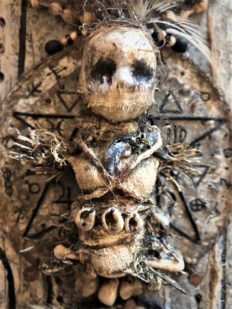 close-up of wall plaque gagged doll on pentagram witch markings on wood