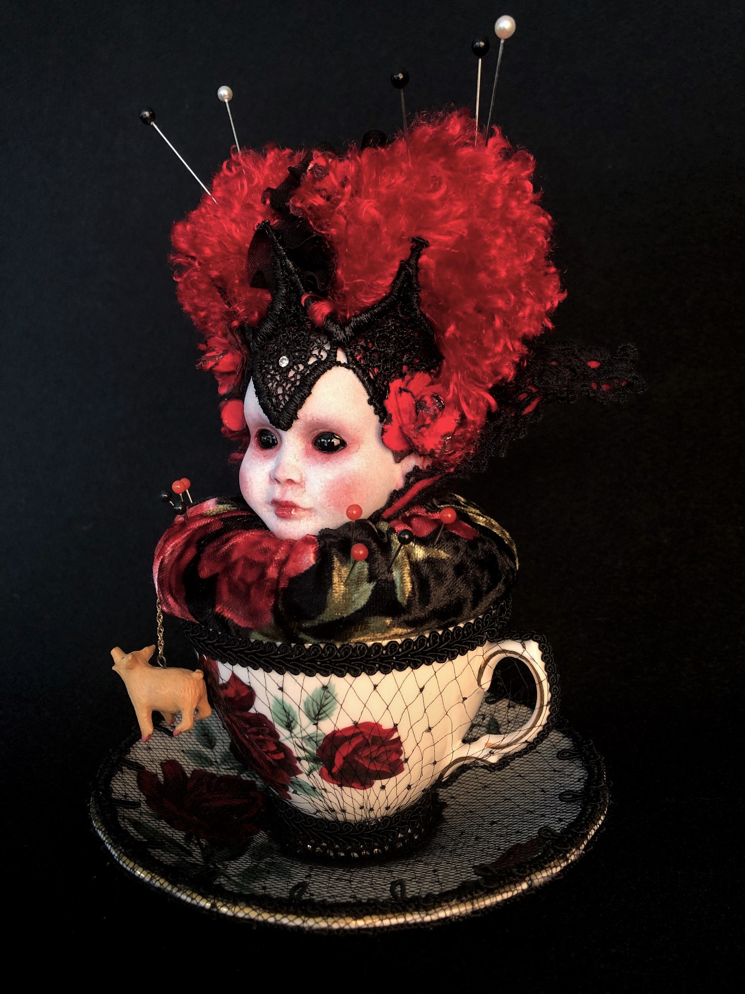 queen of hearts themed velvet pincushion porcelain dollhead sits in a bone china teacup with red roses