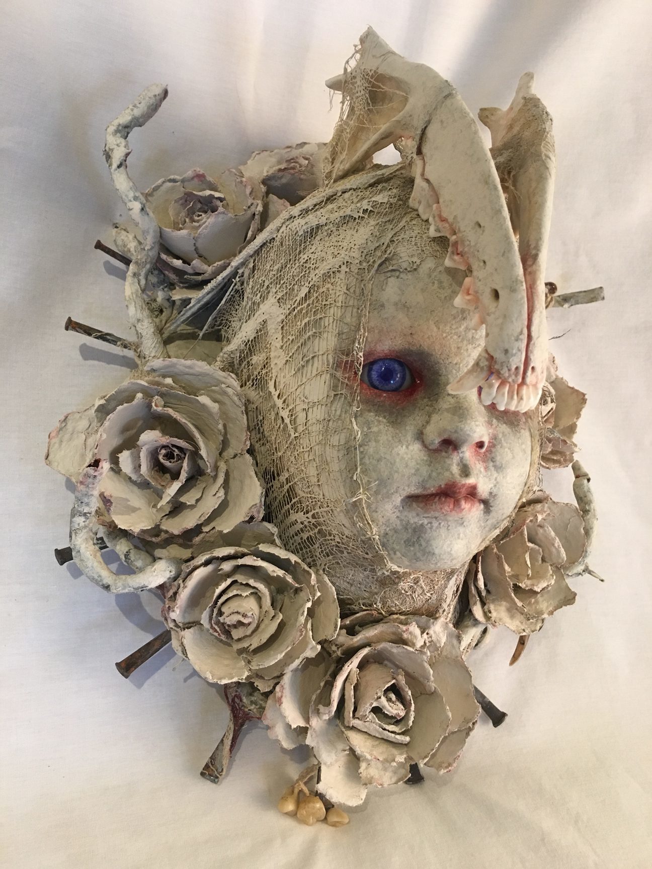 repainted baby doll head bone and white rose headdress red-rimmed blue eyes macabre