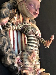 mixed media artpiece mounted on wooden board gothic dark circus-themed toothfairy doll wearing black and white stripes and animal jawbones for wings