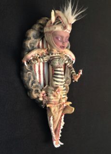 mixed media artpiece mounted on wooden board gothic dark circus-themed toothfairy doll wearing black and white stripes and animal jawbone for a headdress, for wings and a jawbone replacing her legs