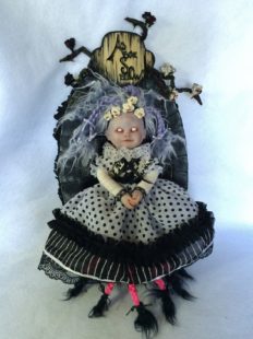 pale gothic artdoll with light purple braids white eyes with no pupils and a white dress with black polkadots mounted on a carved hand-painted wooden plaque